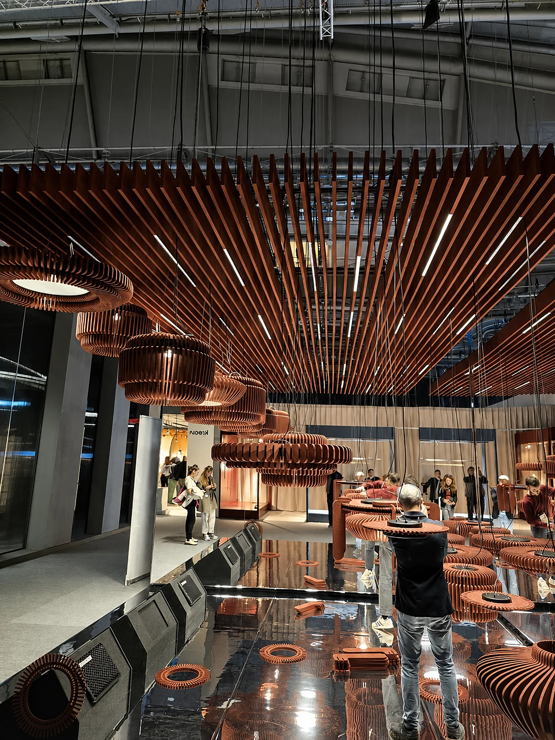 Terracotta acoustic luminaires beneath a linear acoustic ceiling at an exhibition